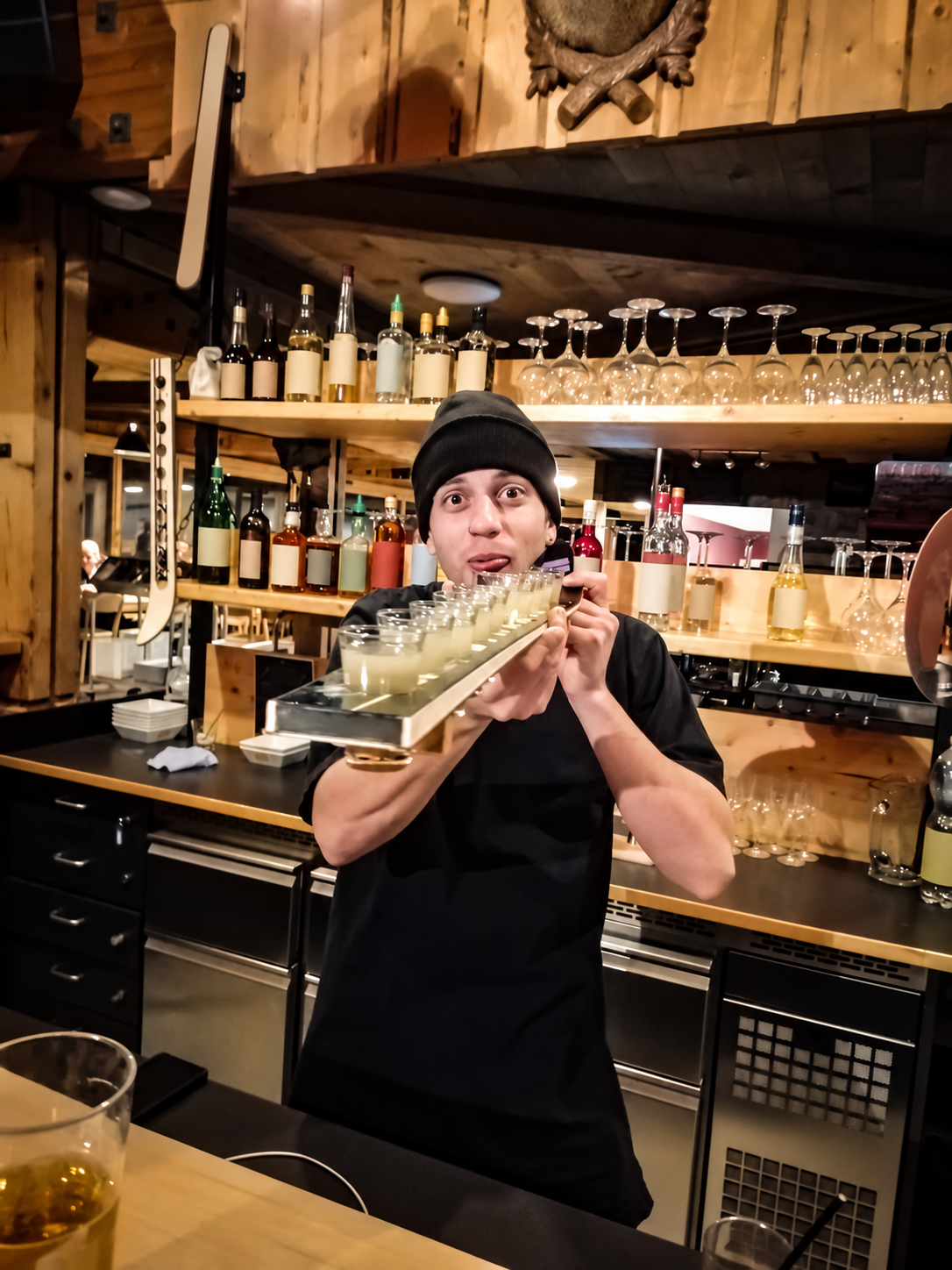 Allrounder mit einem Getränketablett hinter einer rustikalen Bar